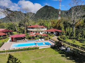 Un resort con piscina, varias edificaciones de techo rojo y abundante vegetación.