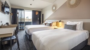 Une chambre d’hôtel avec deux lits, un bureau, une chaise, une télévision et un balcon avec vue.