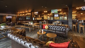 Un espace bar moderne avec des sièges en cuir, des tables en bois et un comptoir.