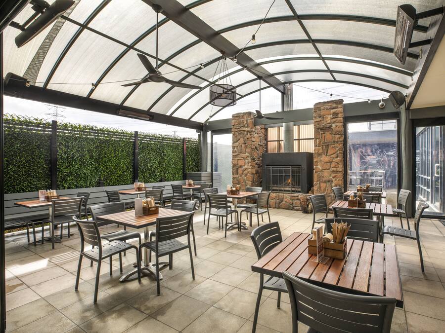 An outdoor patio with tables and chairs, a stone fireplace, and a view of the city.
