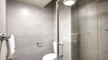 A modern bathroom with a glass-enclosed shower, a toilet, and a towel rack.