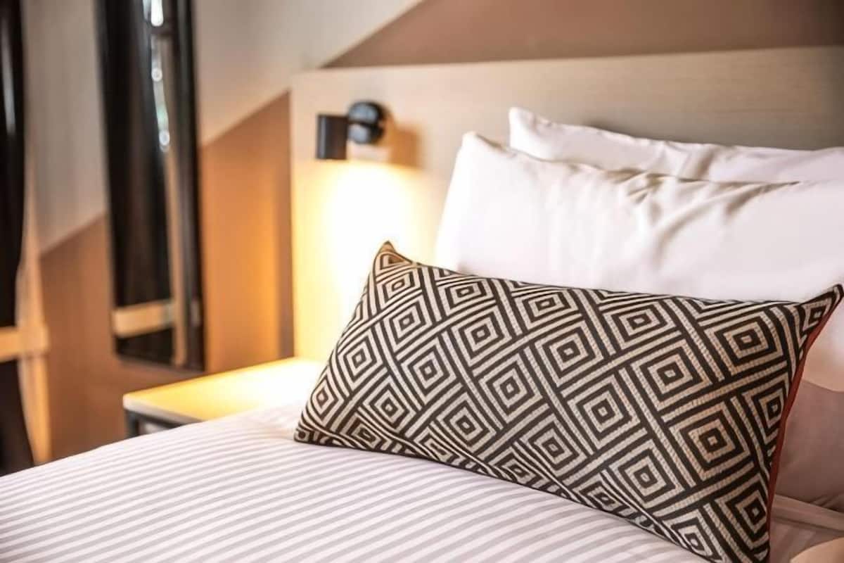 A neatly made bed with patterned pillows, a bedside lamp, and a headboard.
