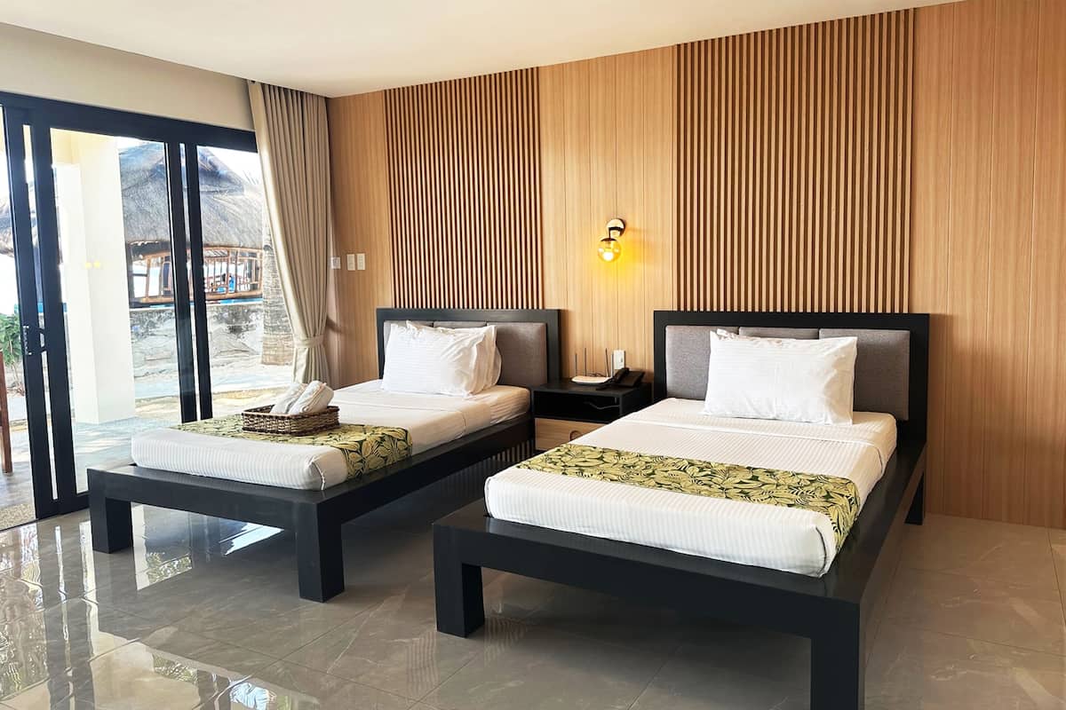 A hotel room with two beds, a large window, and a wooden wall.