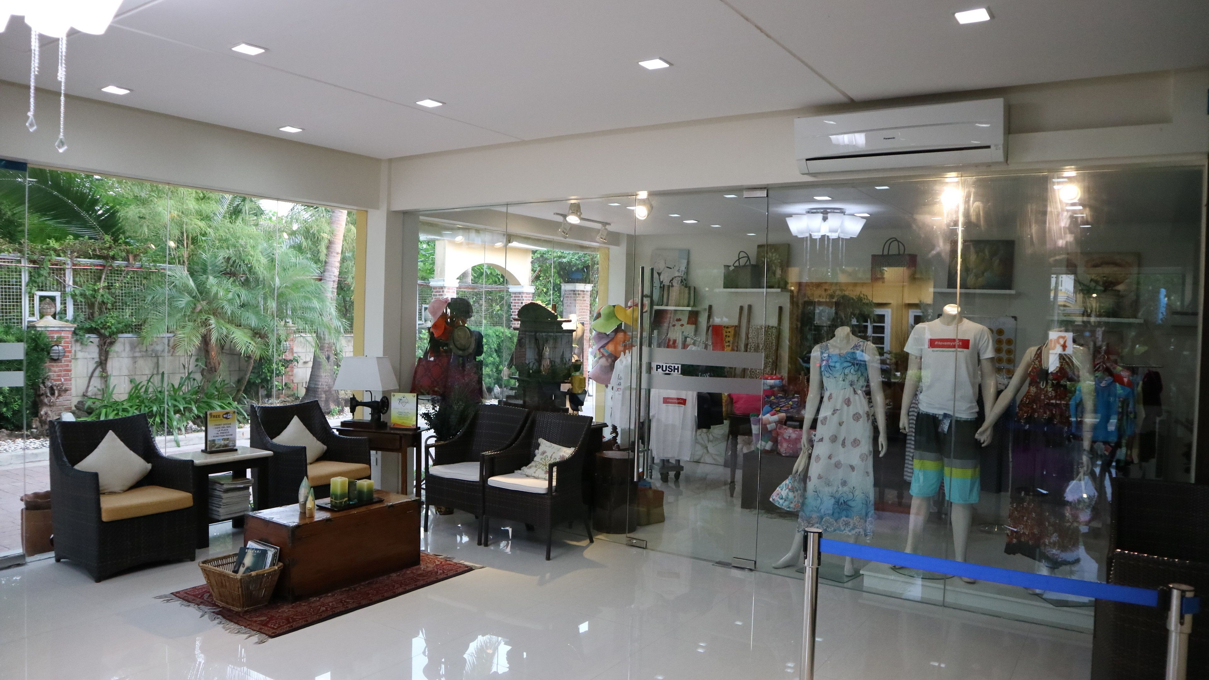 A modern interior with glass display windows, wicker furniture, and a view of greenery outside.