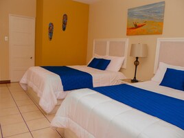 Una habitación de hotel con dos camas, una puerta, un cuadro y una lámpara.