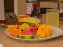 A breakfast plate with various fruits and a glass of juice.