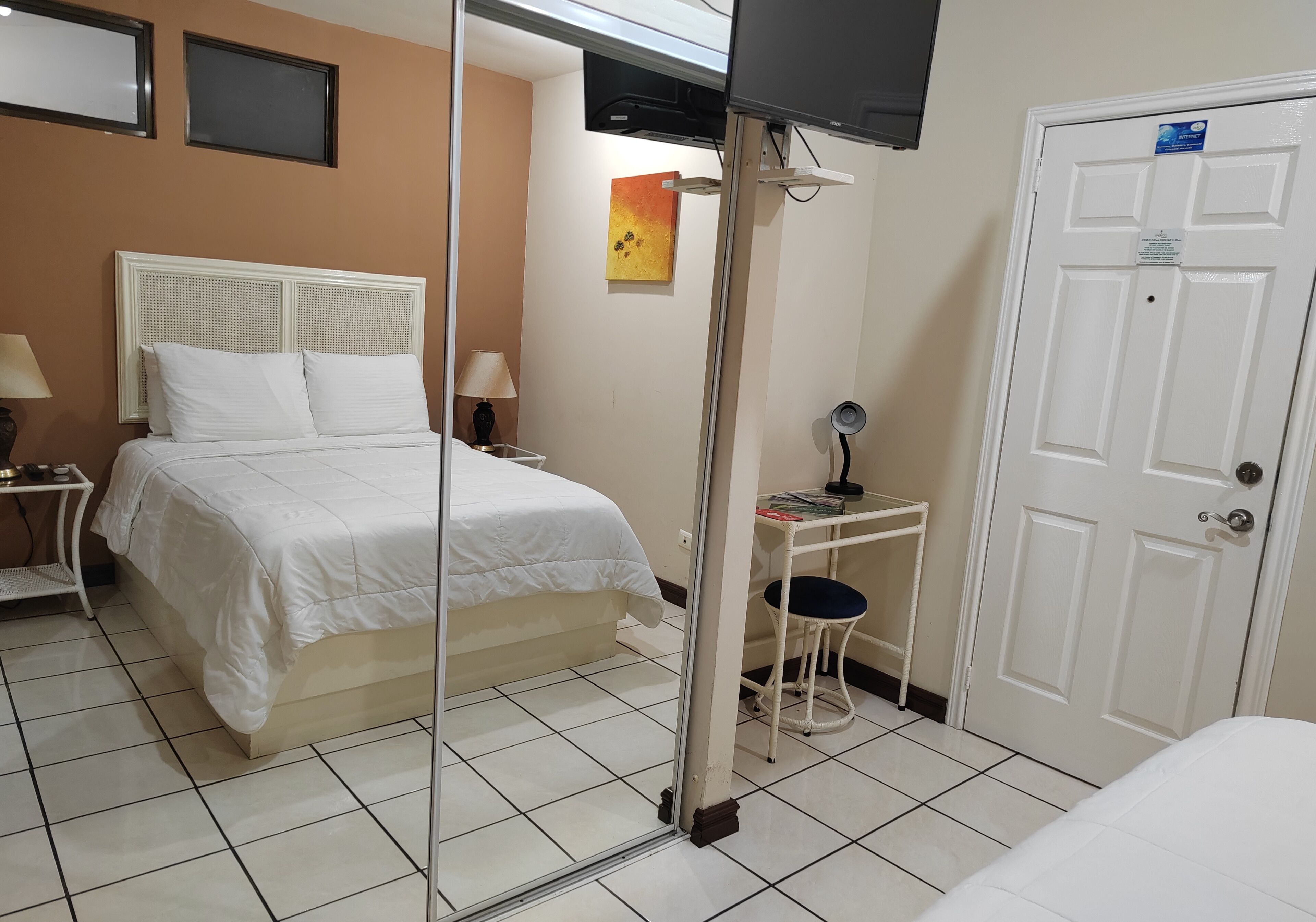 Een hotelkamer met een bed, een bureau, een stoel, een televisie en een deur.