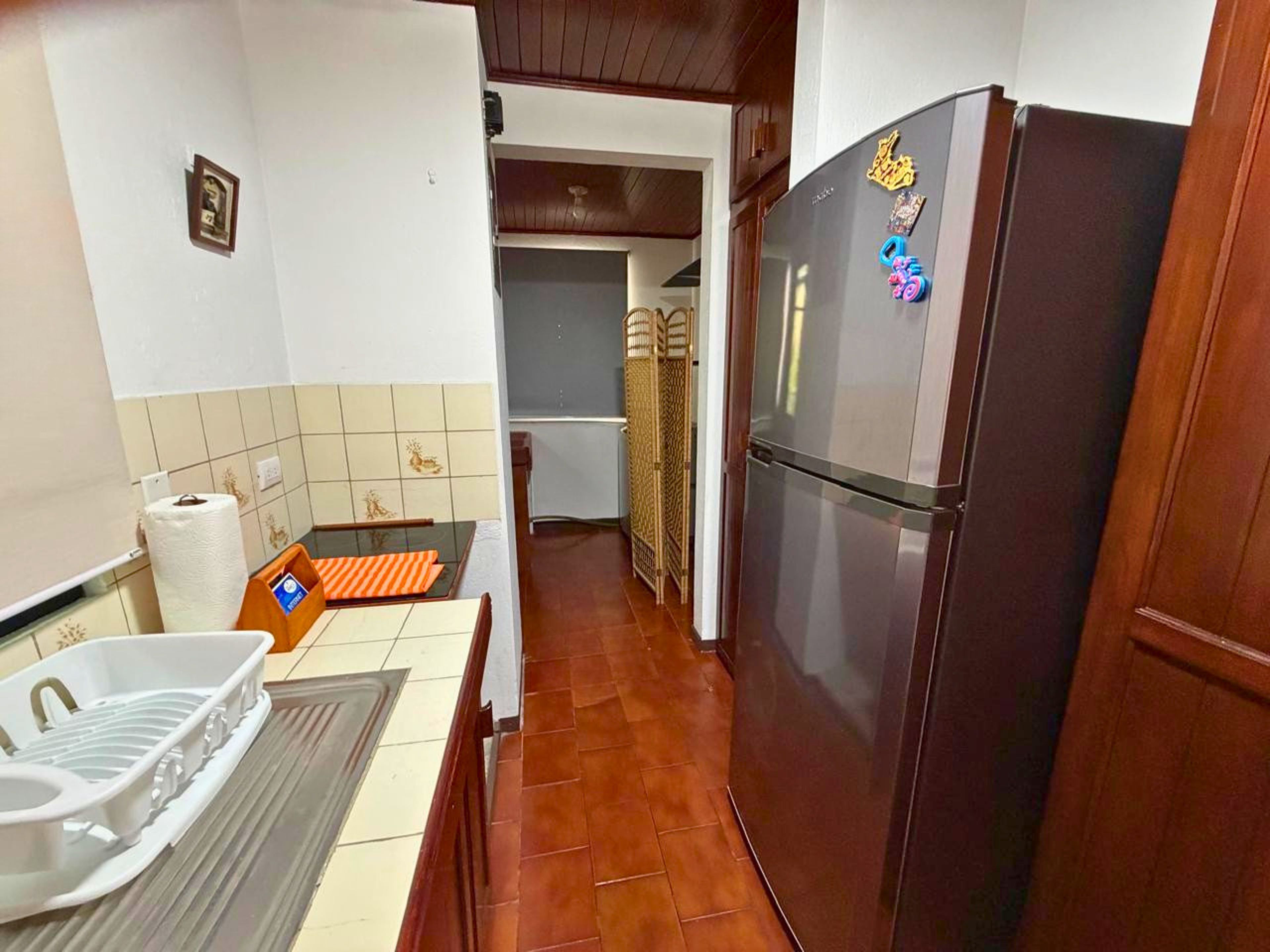 A kitchen with a refrigerator, a sink, and a tiled backsplash.