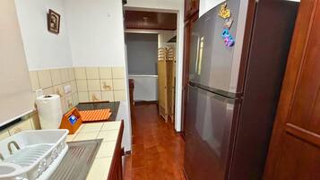 A kitchen with a refrigerator, a sink, and a tiled backsplash.