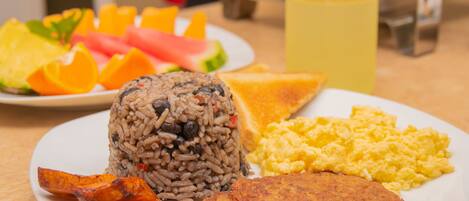 A plate of food with rice, eggs, plantains, and toast.