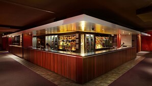 Una zona de bar con mostrador, estantes llenos de botellas y un cartel que dice 