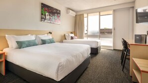 Una habitación de hotel con dos camas, un escritorio, una silla, un televisor y un cuadro en la pared.