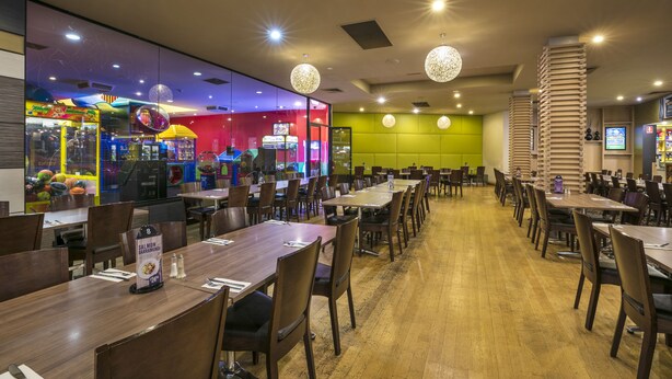 Un restaurante con varias mesas y sillas, una barra con una exhibición colorida y un letrero de neón.