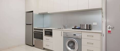 Una cocina moderna con electrodomésticos de acero inoxidable, horno empotrado, lavadora y microondas.