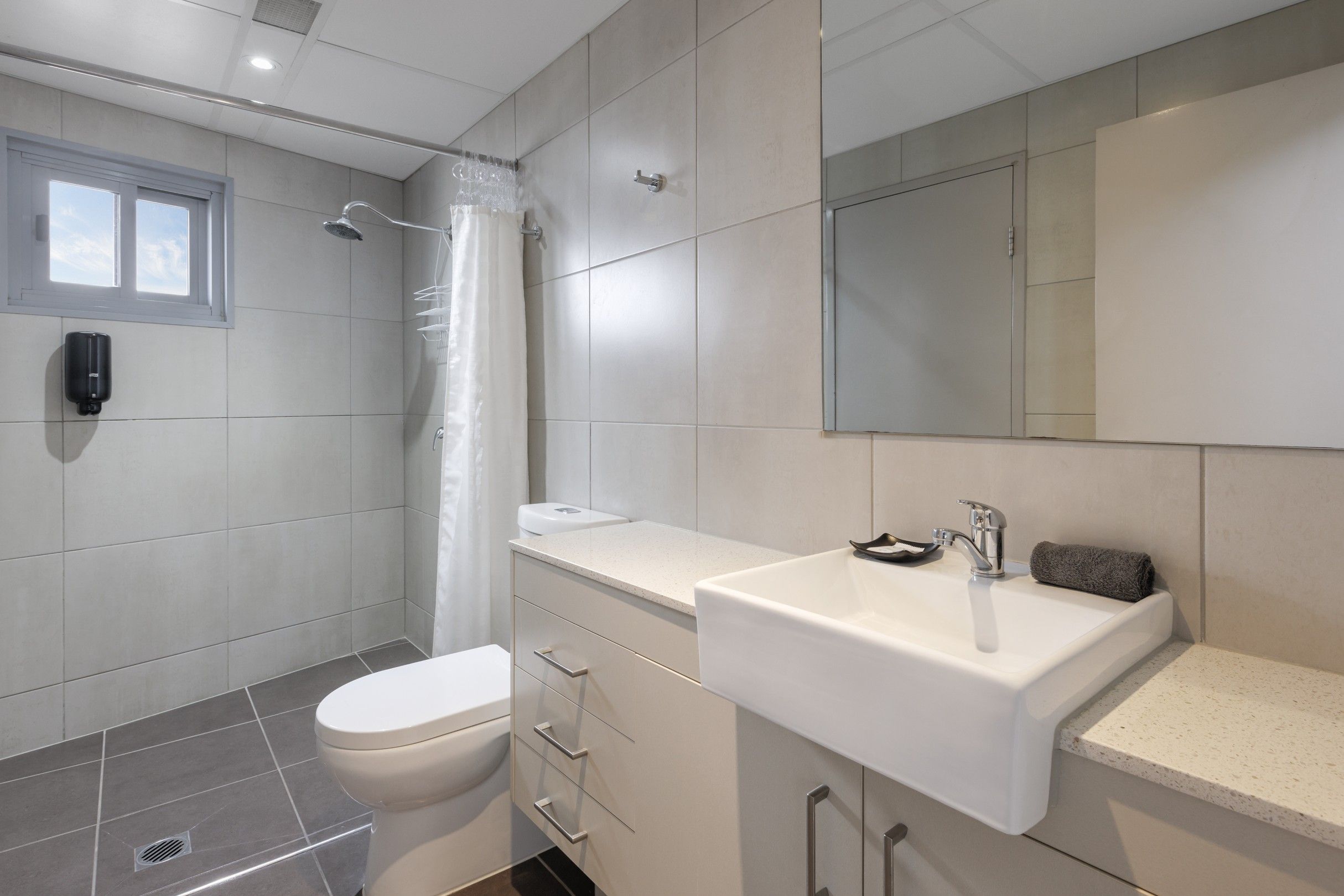 A modern bathroom with a shower, toilet, and sink.