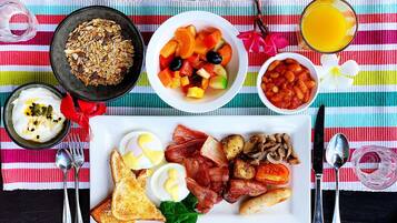 Ein reichhaltiges Frühstücksbuffet mit Toast, Eiern, Speck, Pilzen und einer Obstschale.