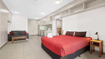A modern bedroom with a large bed, a sofa, a small table, and a mirror.