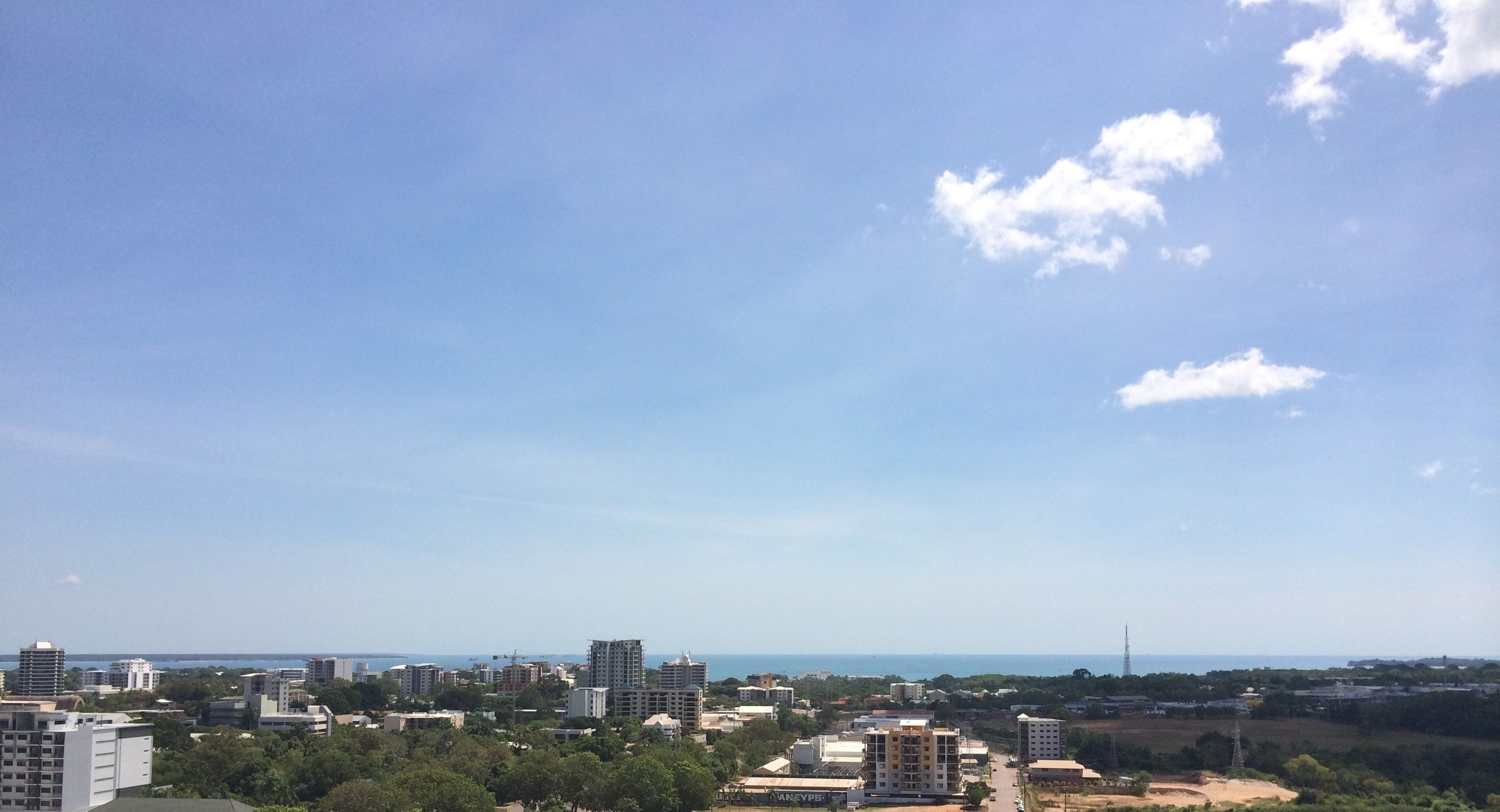 Un paysage urbain avec de nombreux gratte-ciel, un ciel dégagé et une vue lointaine sur la mer.