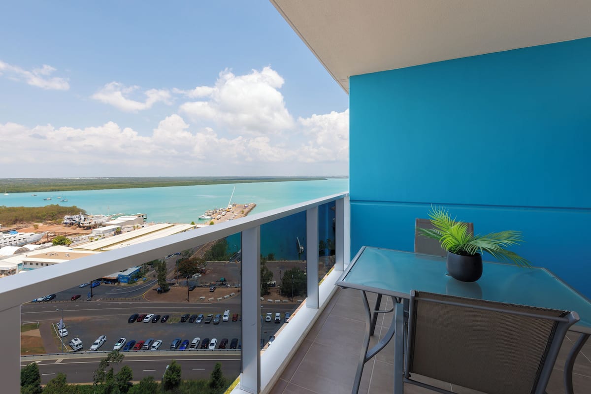 Un balcon avec vue sur une marina et un ciel dégagé.