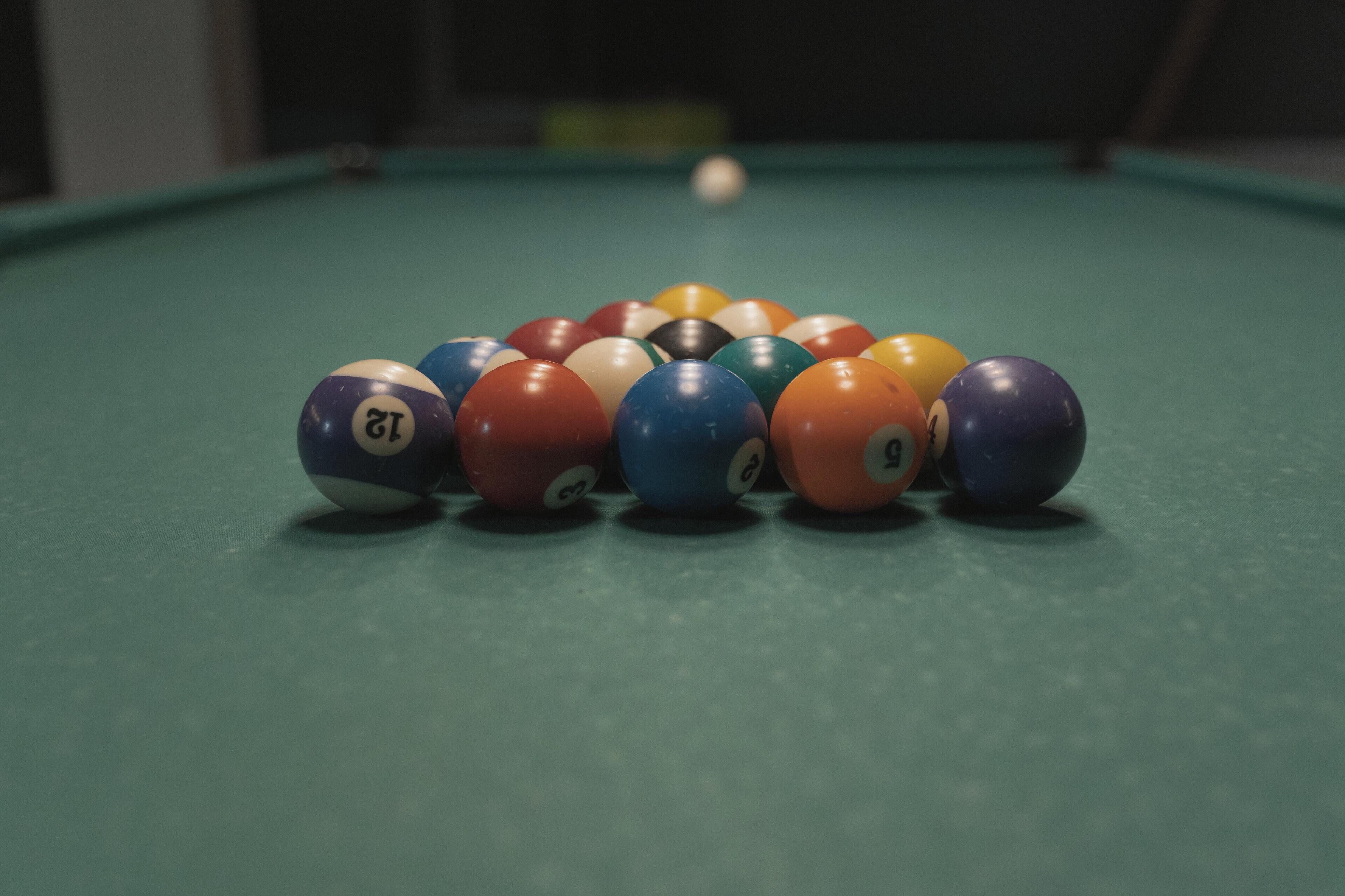 Une table de billard avec un jeu de billes disposées en forme de triangle.