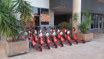 A row of red electric scooters parked in front of a building with a 'Zen' sign.