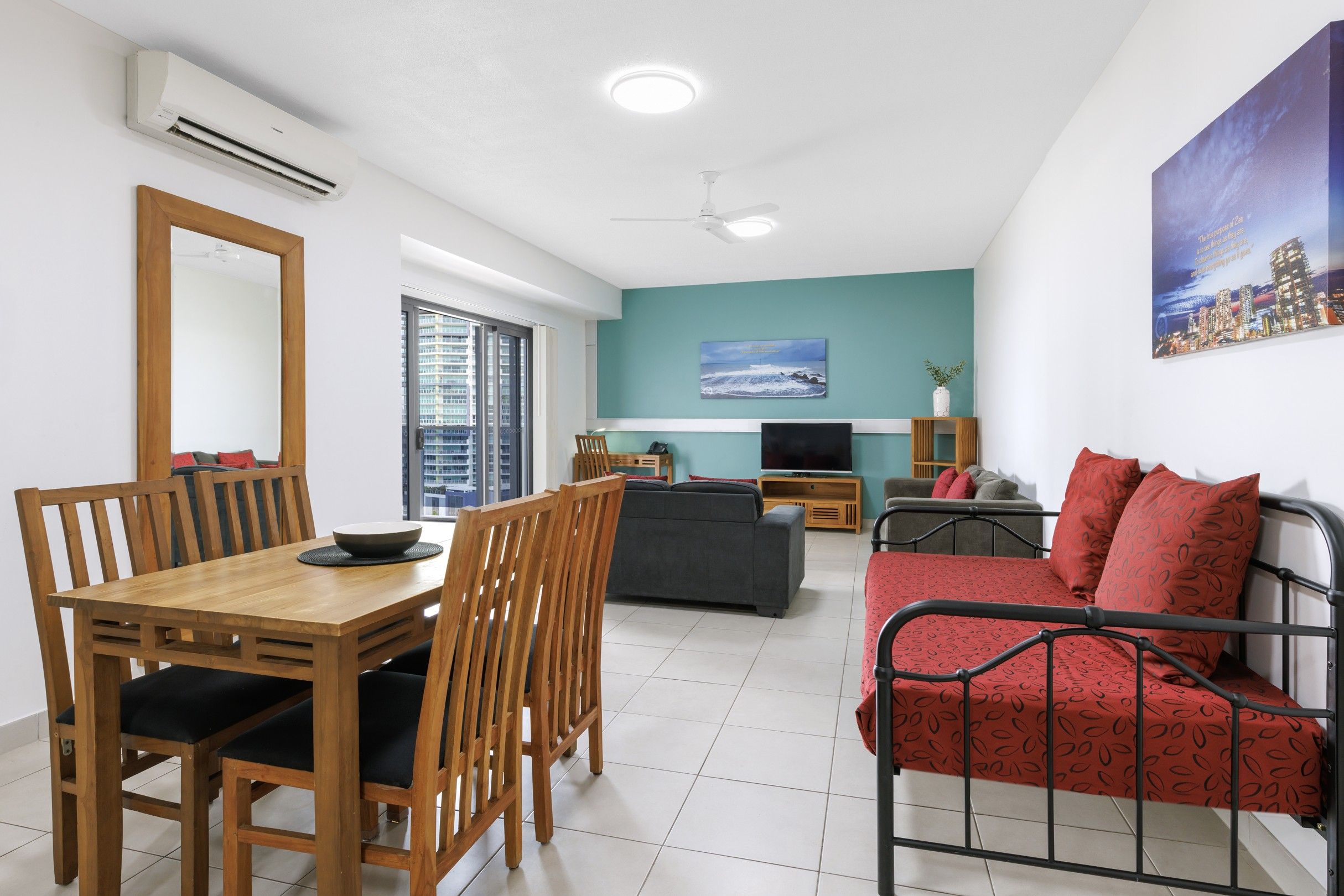 A modern living room with a dining area, a sofa, a TV, and a cityscape painting.