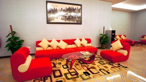 A modern living room with a red sofa set, a glass coffee table, and a framed picture on the wall. - Princeton Hotel (Johor Bahru)