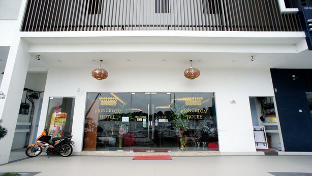 The entrance of Princeton Hotel with a modern design, featuring large glass doors, a red mat at the entrance, and two hanging spherical lights. - Princeton Hotel (Johor Bahru)