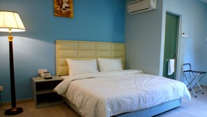 A hotel room with a bed, bedside table, lamp, and a folding chair. - Princeton Hotel (Johor Bahru)