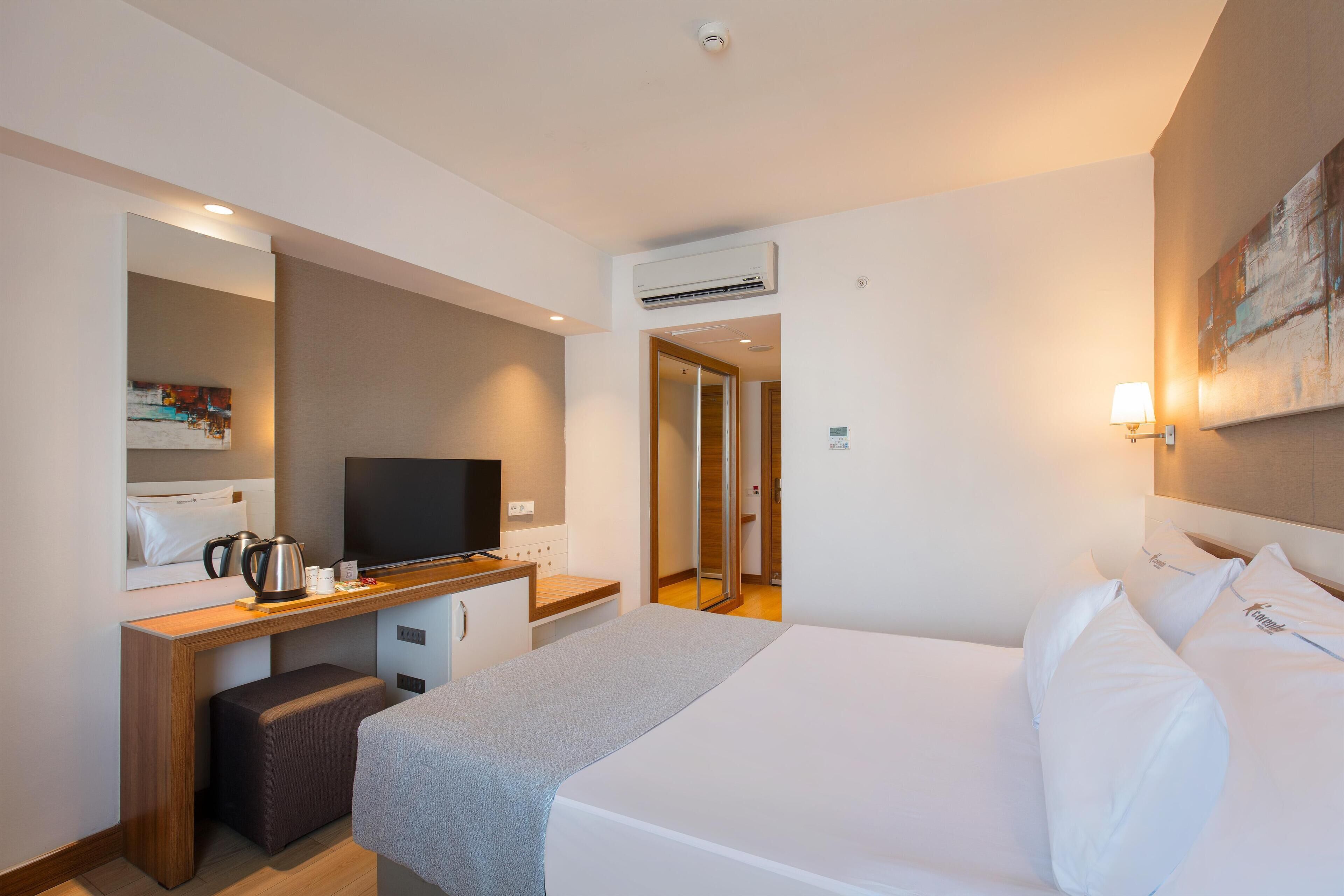 Une chambre d’hôtel comprenant un lit, un bureau avec une télévision, une machine à café et un miroir.
