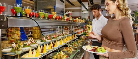 A buffet with various food and drink options, including salads, cheeses, and colorful beverages.