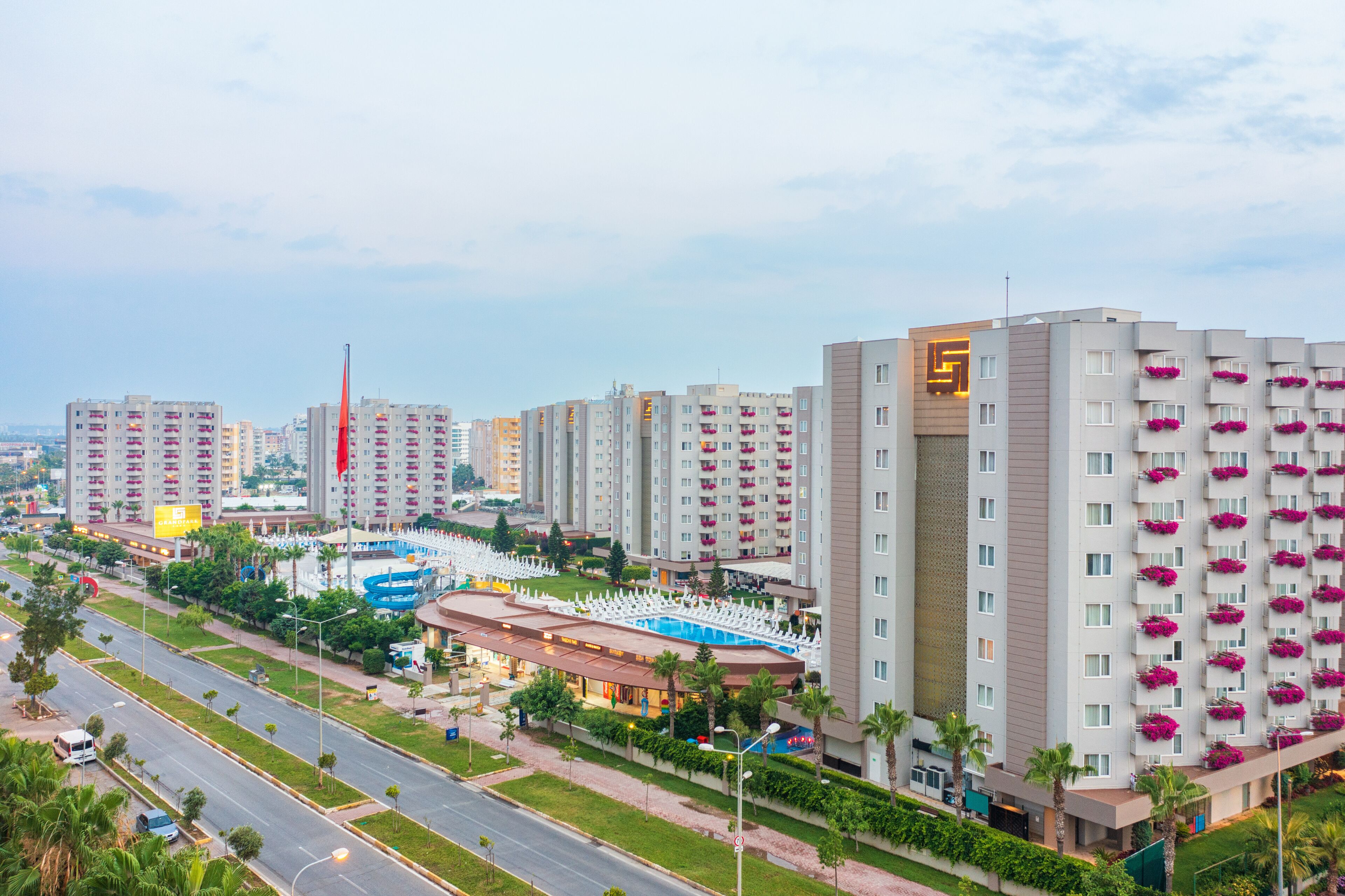 A modern hotel complex with multiple high-rise buildings, a swimming pool, and a well-maintained surrounding area.