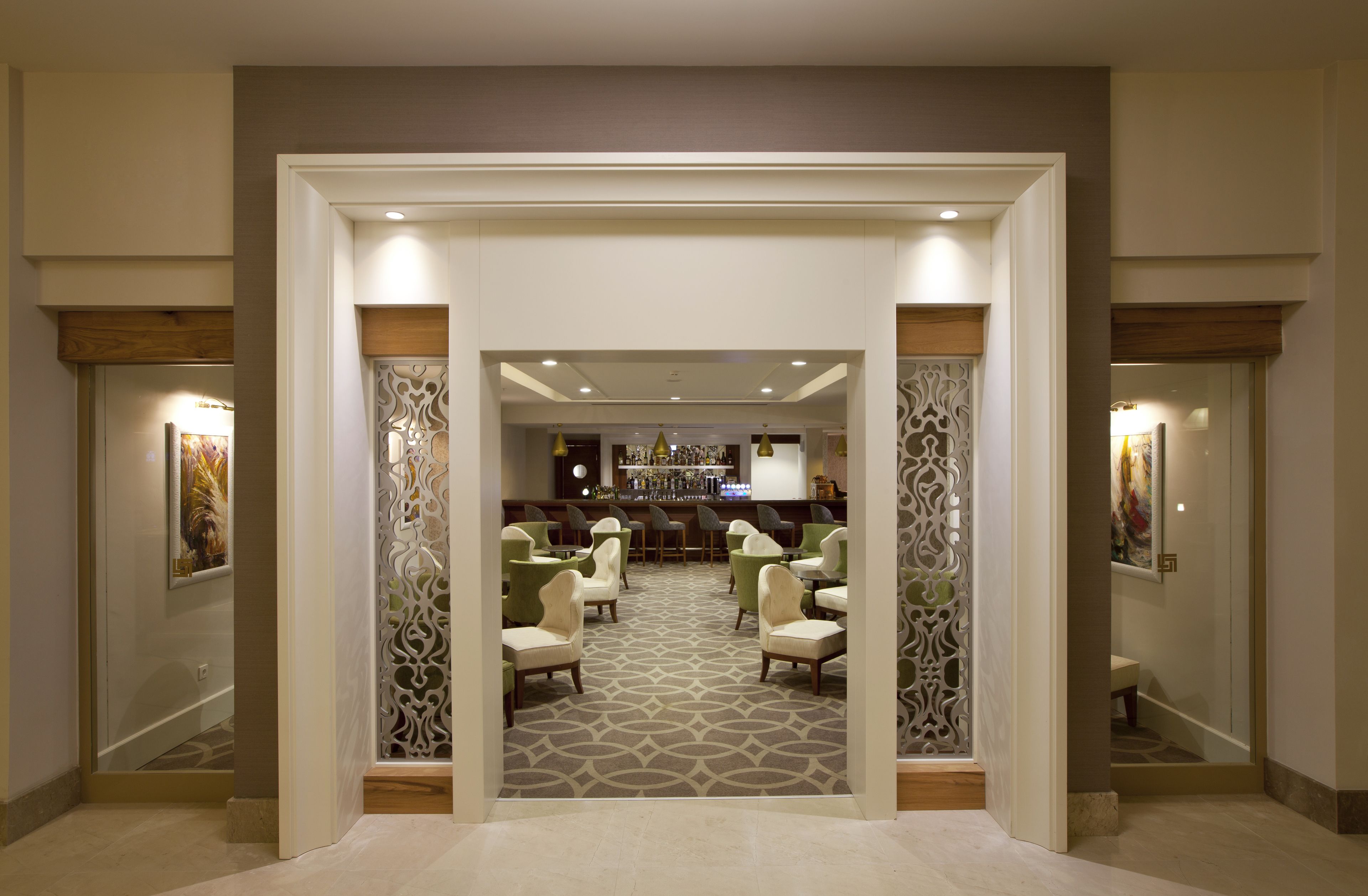 A hotel lobby with a bar area, seating, and decorative panels.