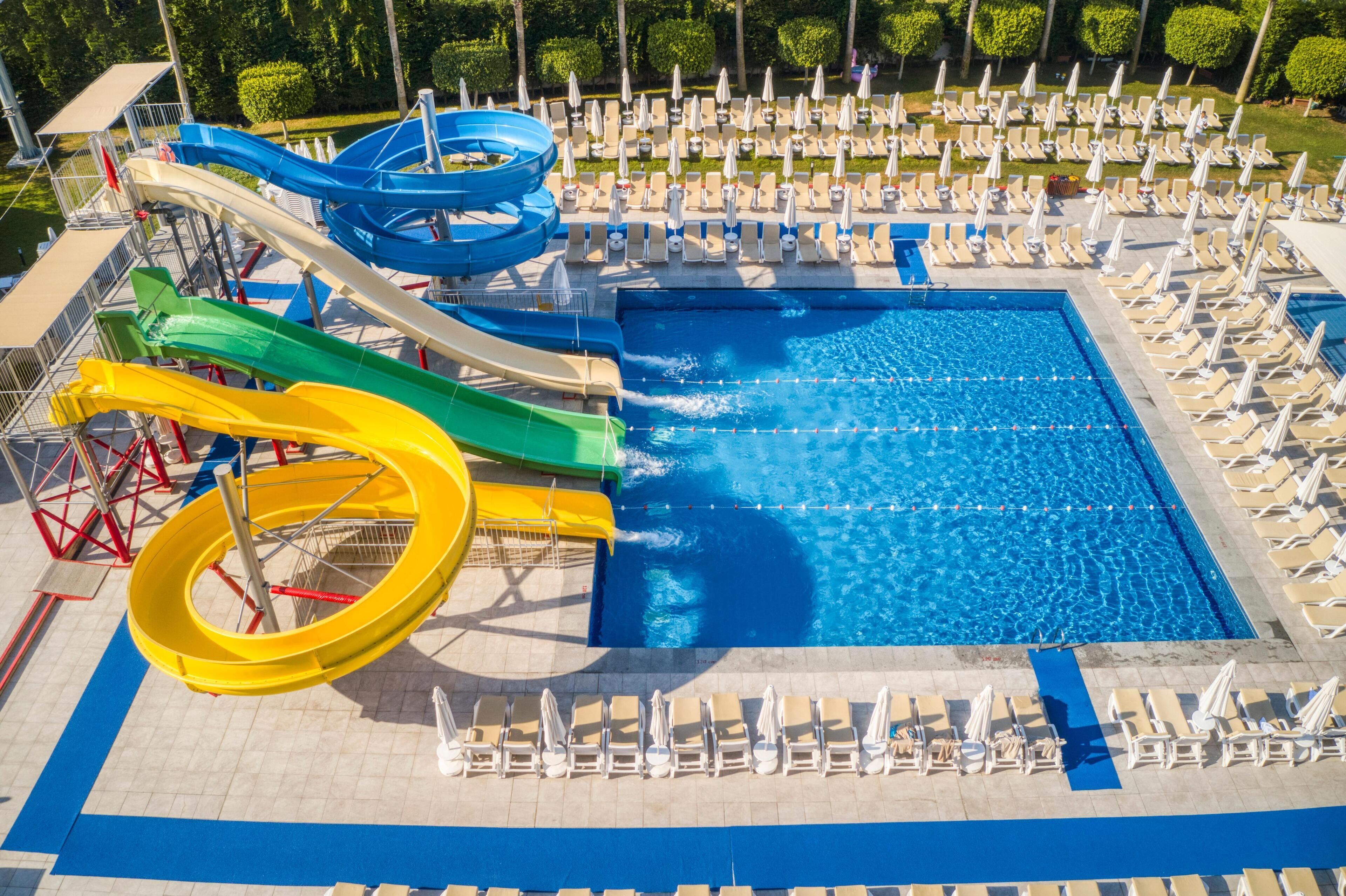 A swimming pool with multiple water slides and sun loungers arranged around it.
