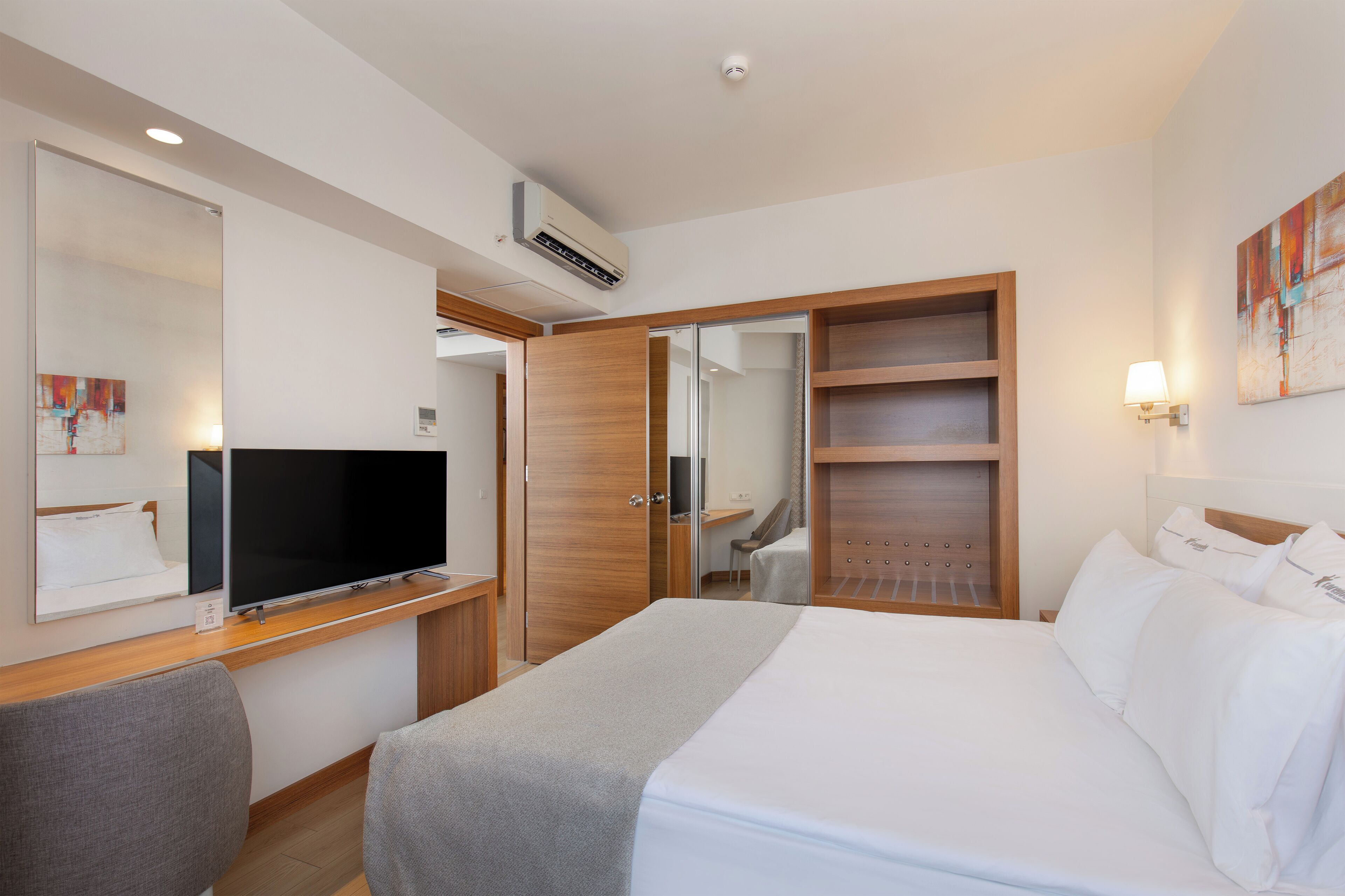 Una habitación de hotel con cama, televisión, escritorio y armario.
