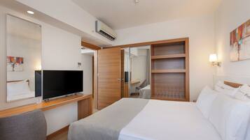 Una habitación de hotel con cama, televisión, escritorio y armario.