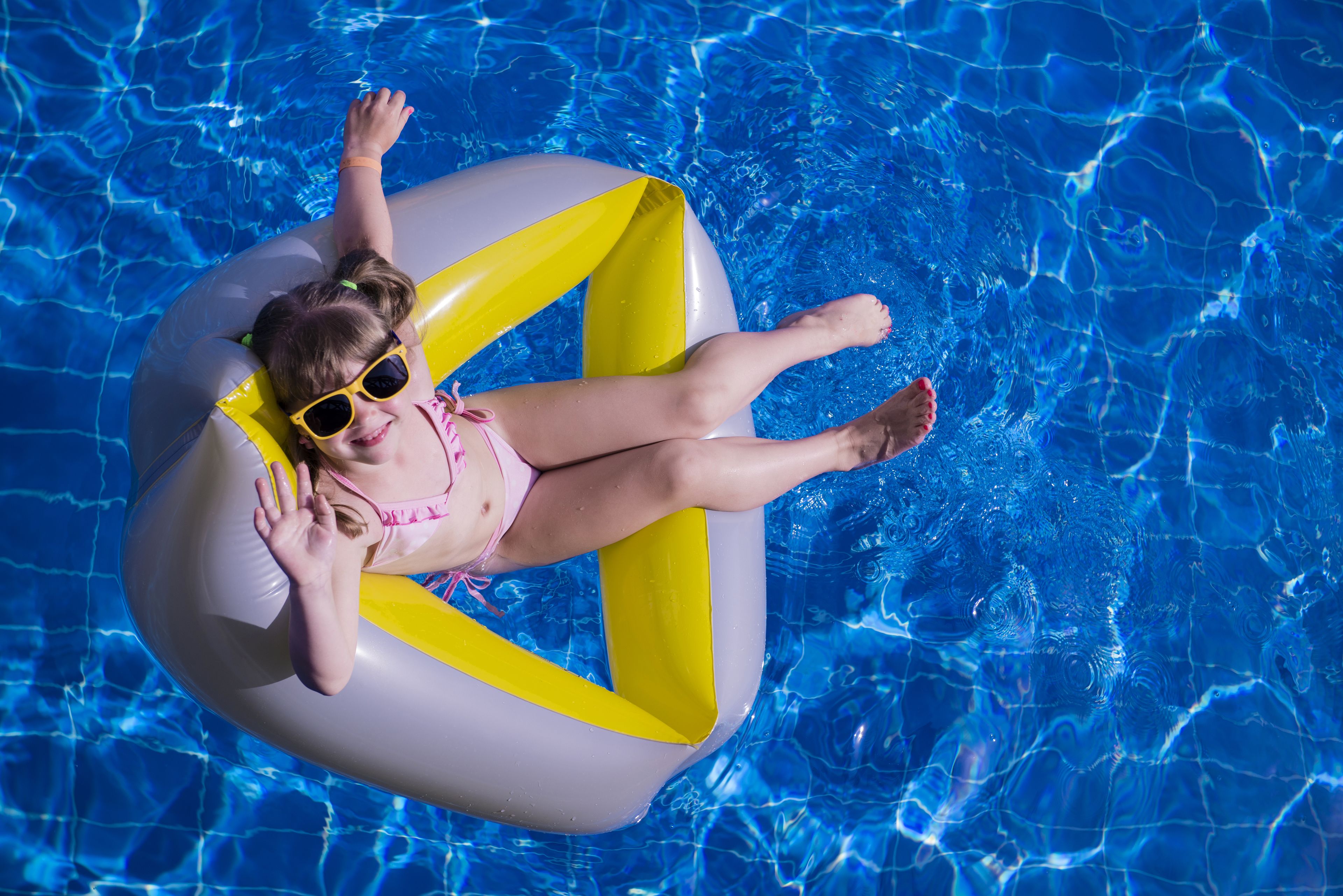 Una persona flota en una balsa inflable dentro de una piscina.