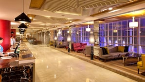 A hotel lobby with a reception desk, seating area, and modern lighting fixtures. - Corendon Grand Park Lara - Ultra All Inclusive (Antalya)