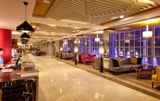 Un vestíbulo de hotel con recepción, zona de estar e iluminación moderna.