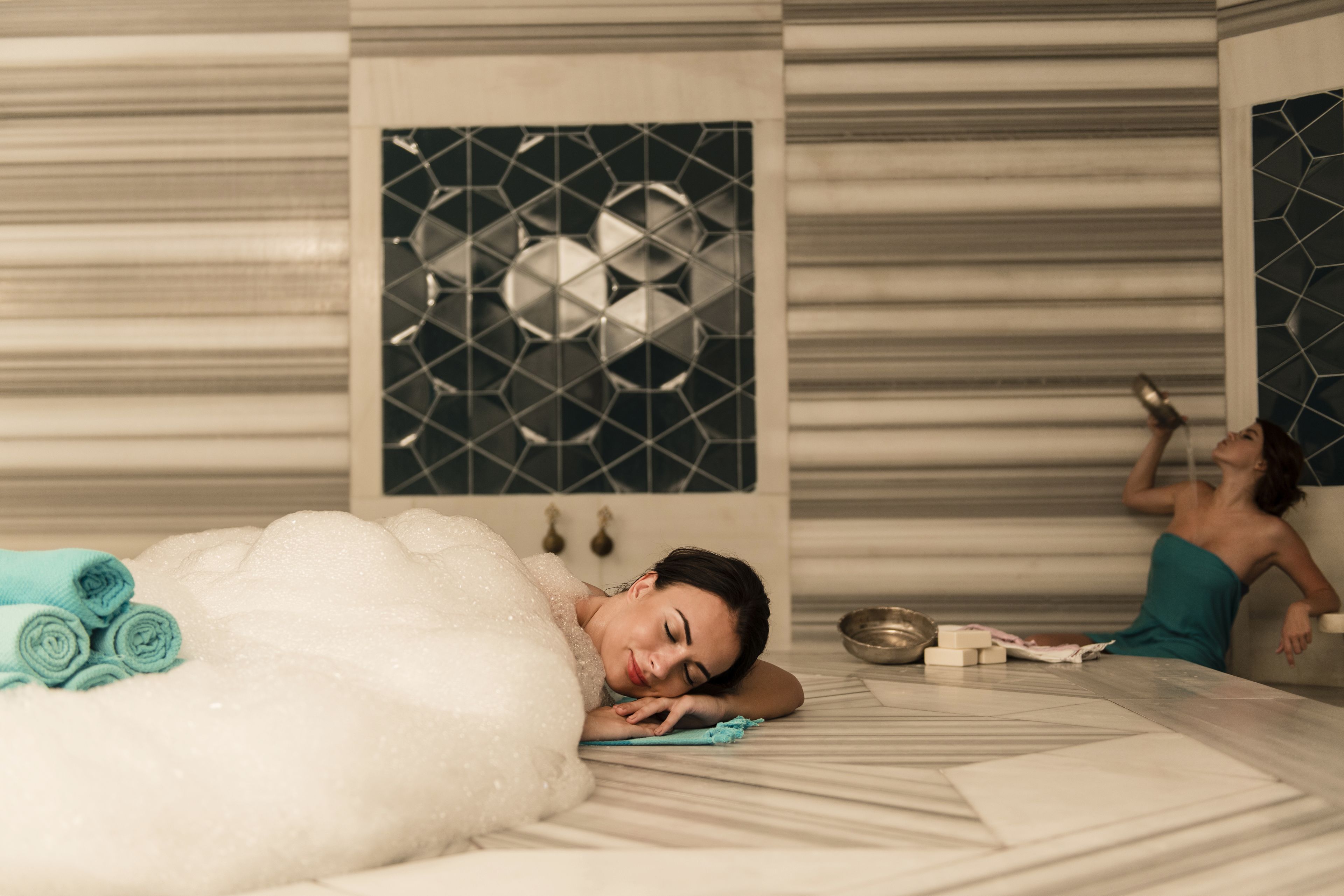 Une salle de spa équipée d’une table de massage, de serviettes et d’un mur décoratif.