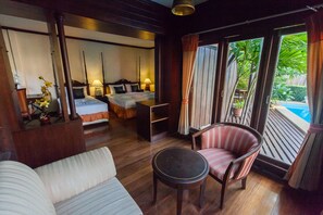 A hotel room with a bed, bedside table, lamp, and a view of a pool. - Phangan Paragon Resort & Spa (Ko Pha-ngan)
