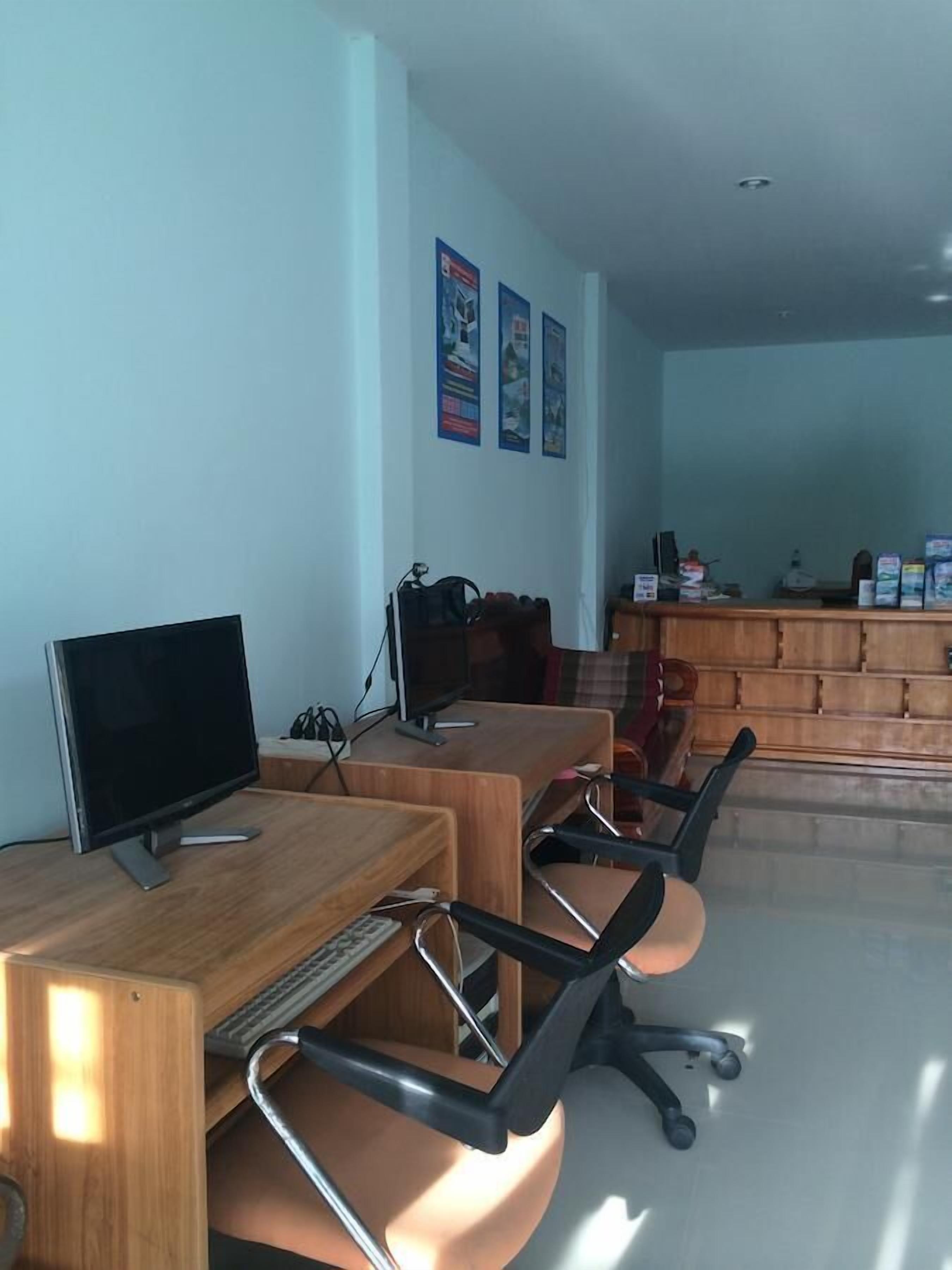 Un salón de conferencias con dos escritorios, sillas, un mostrador de recepción de madera y una pared con carteles.