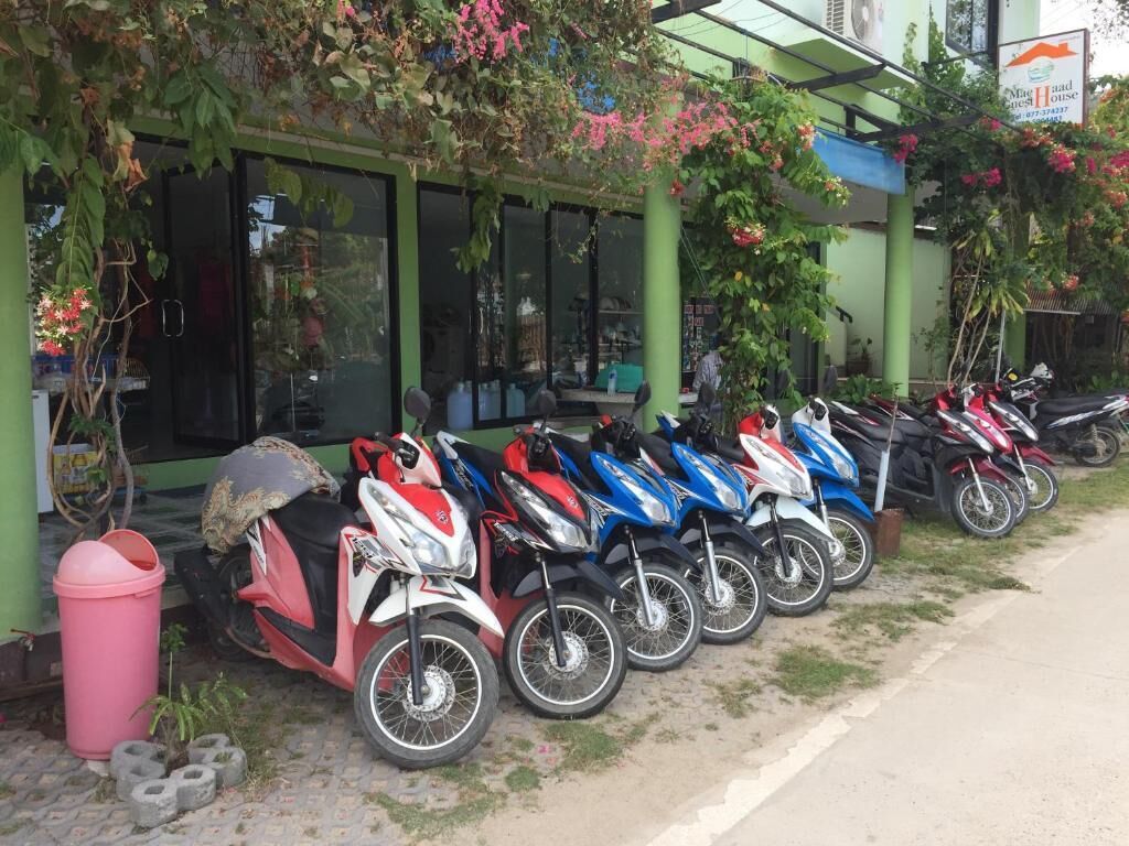 Varias motocicletas estacionadas frente a un edificio de fachada verde y un letrero.