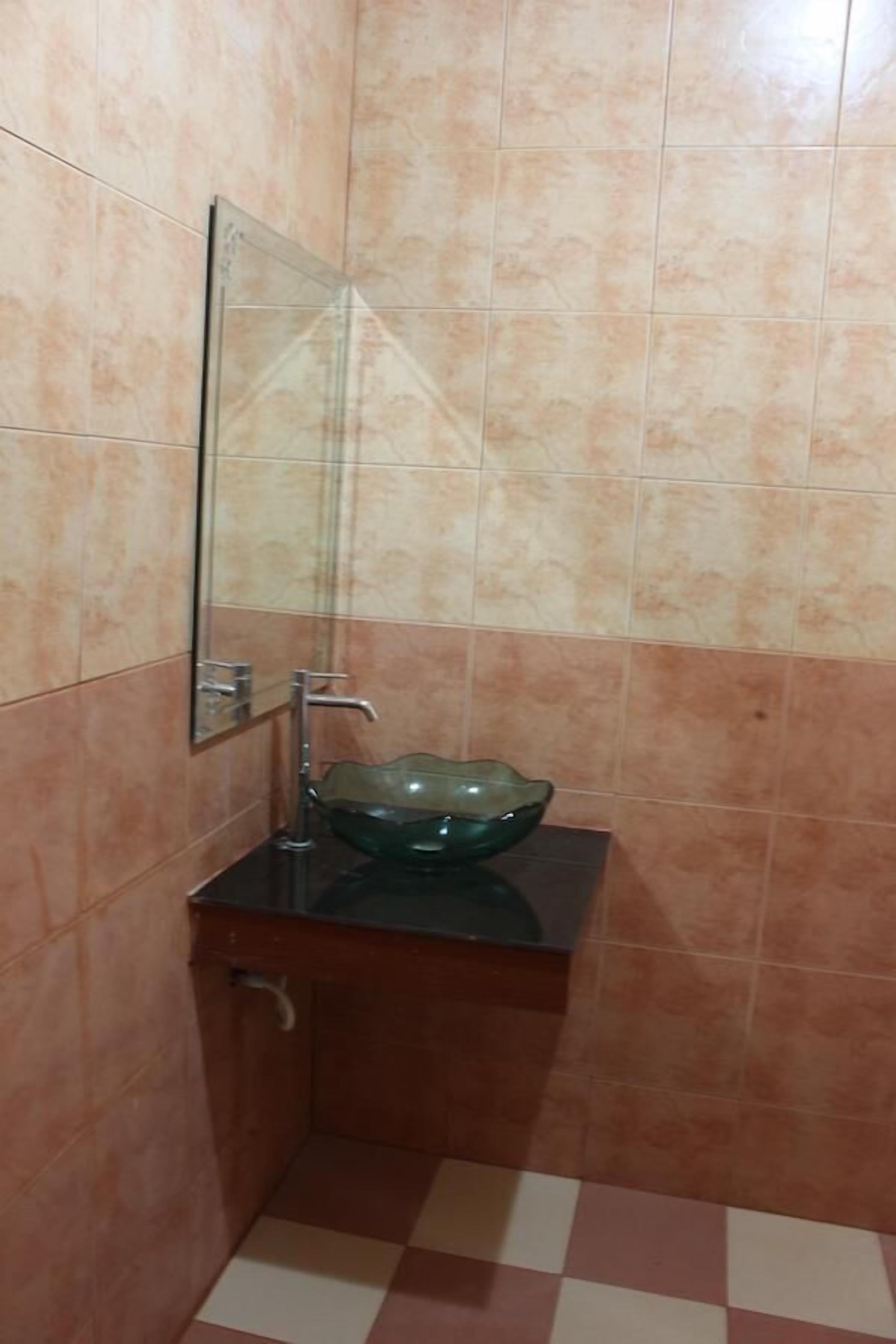 Ein Badezimmer mit einem Waschbecken aus Glas, einem Spiegel und einem gefliesten Boden.