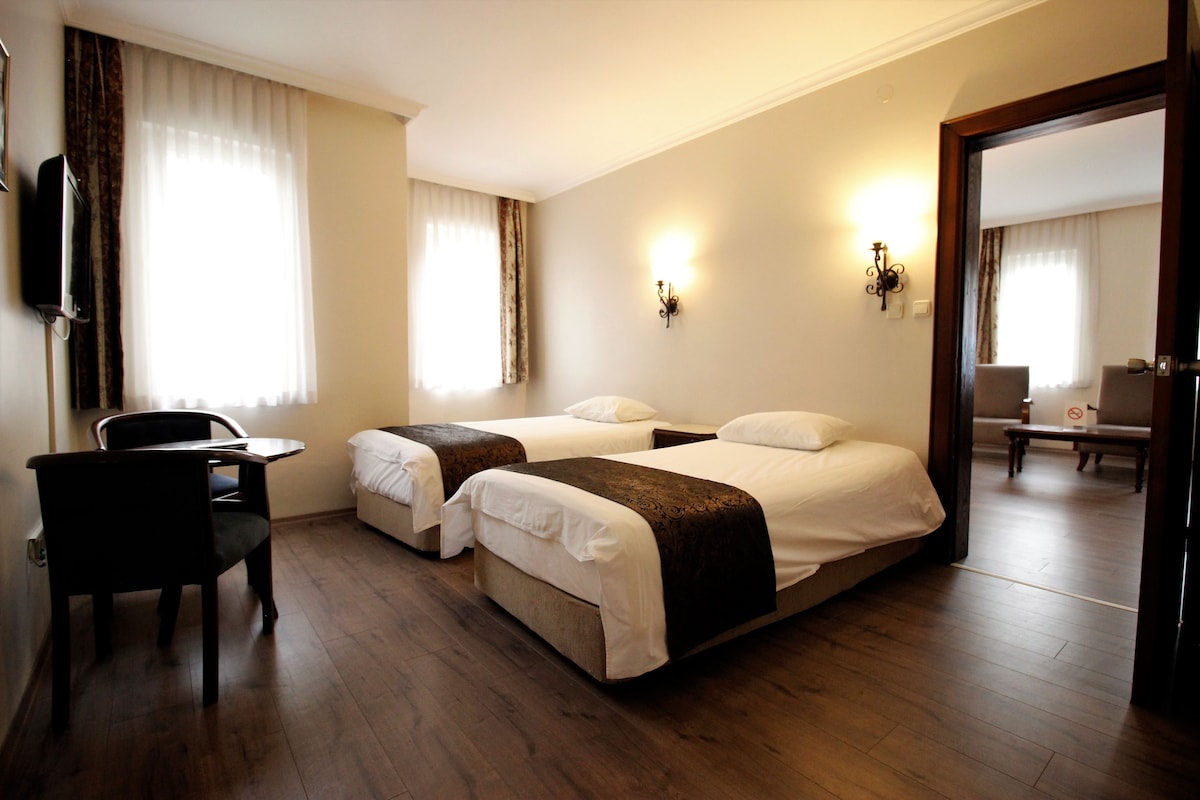 Een hotelkamer met twee bedden, een bureau en een stoel.
