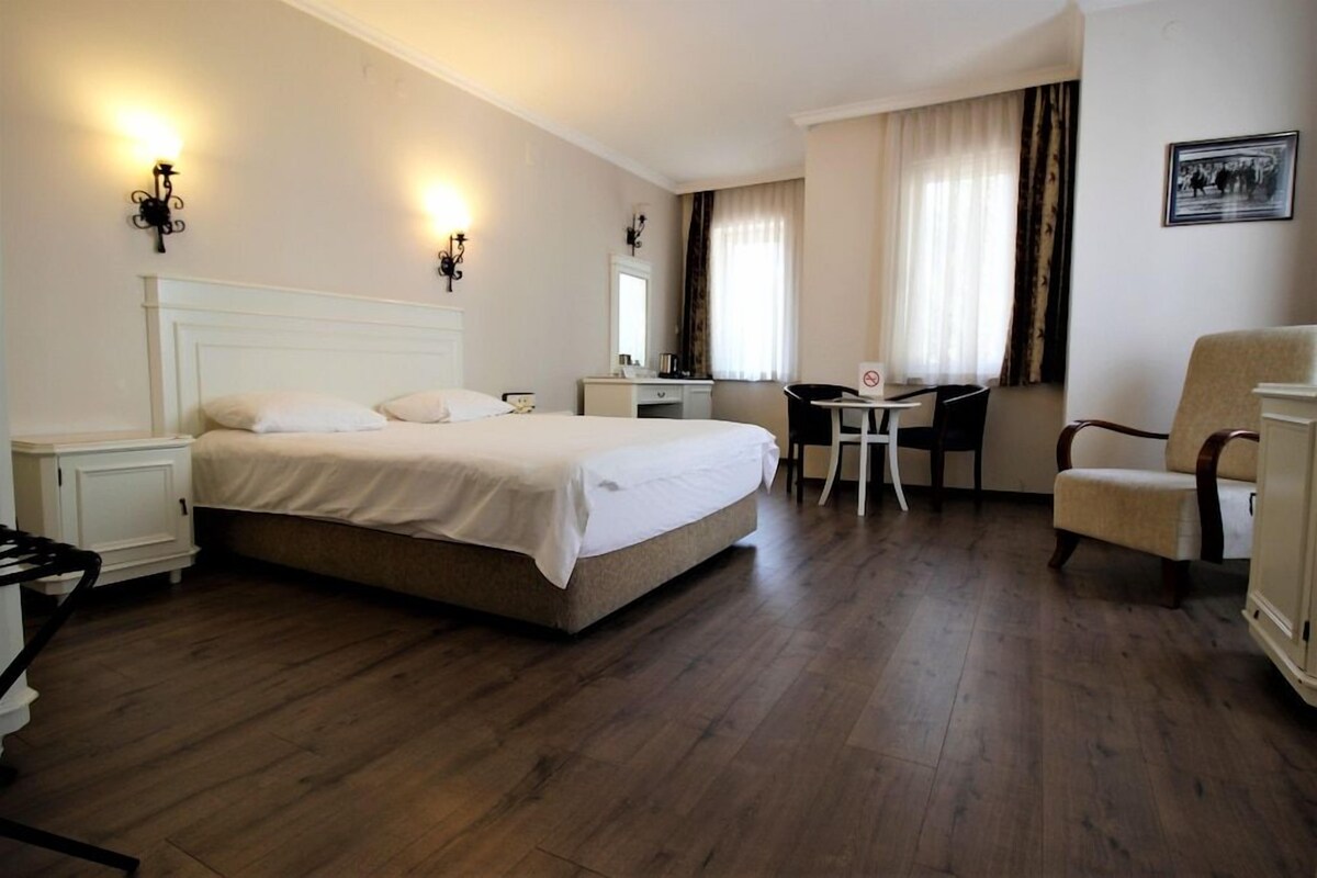 Ein Hotelzimmer mit einem großen Bett, einem Schreibtisch, einem Stuhl und einem kleinen Tisch.