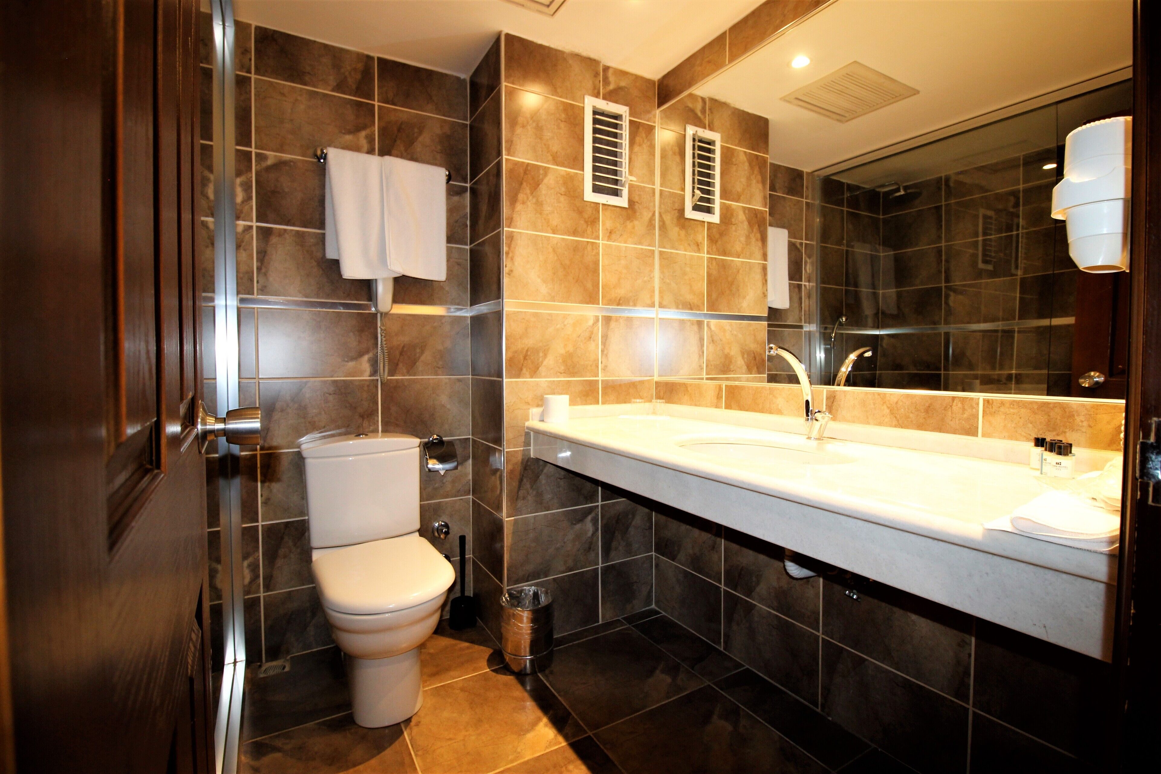 A modern bathroom with a toilet, sink, and mirror.