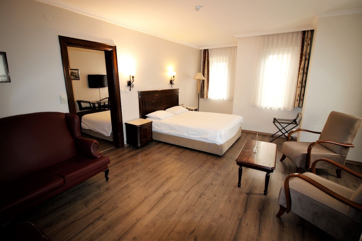 Une chambre d’hôtel avec un lit, un fauteuil rouge, une table basse en bois et une chaise.