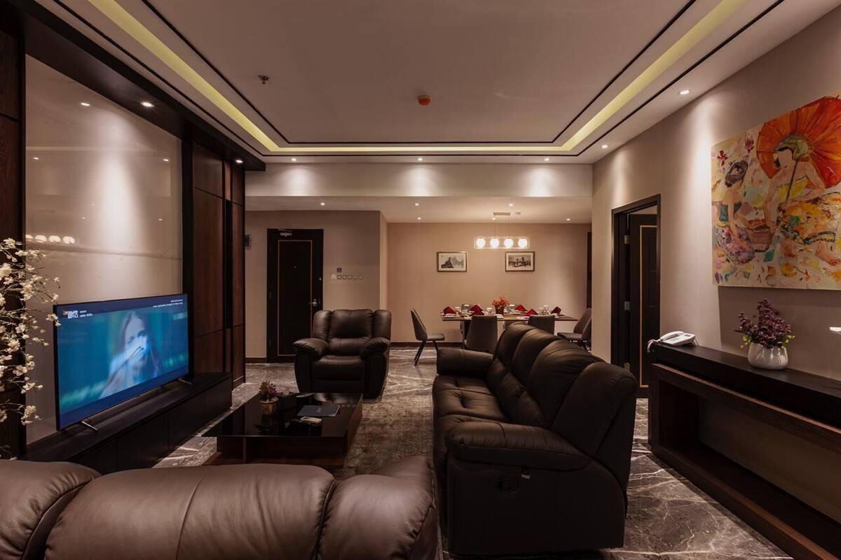Eine moderne Hotelhalle mit Ledersofas, einem Flachbildfernseher, einer Rezeption und einem Essbereich.