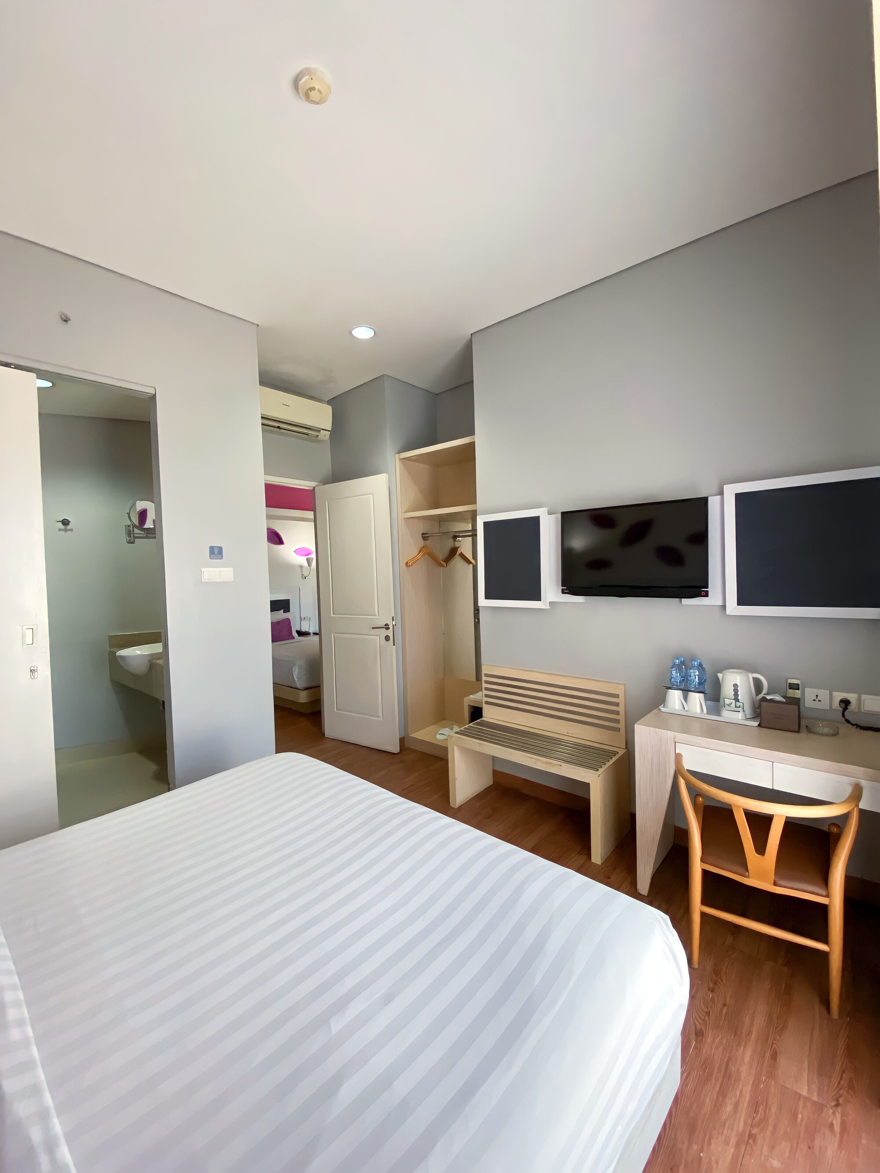Una habitación de hotel con cama, escritorio, silla, armario y televisor.